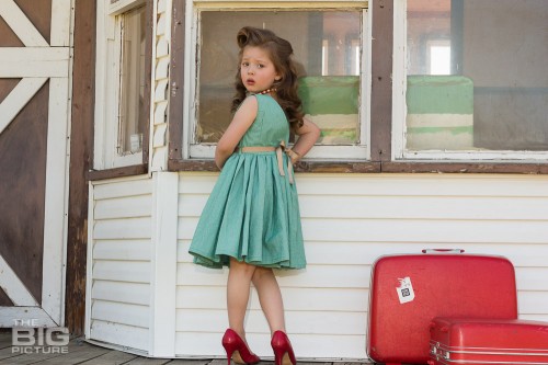children's photography, children's portraits, young girl at train station with luggage in a green dress with vintage hair