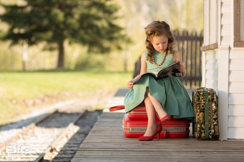 children's photography, vintage children's portraits, little girl sitting on suitcases reading a marilyn monroe magazine at a railway station