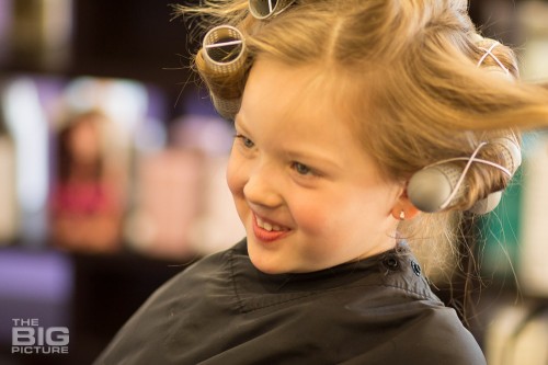 children's photography, young girl in a salon with curlers in her hair smiling, retro children
