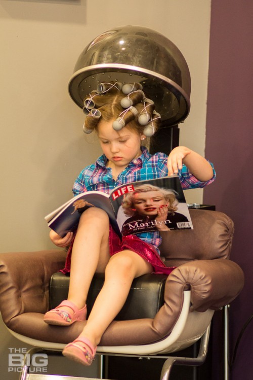 children's photography, young girl with curlers in her hair under a hair dryer looking at a Marilyn Monroe magazine, life magazine, kid's retro hair, vintage rockabilly